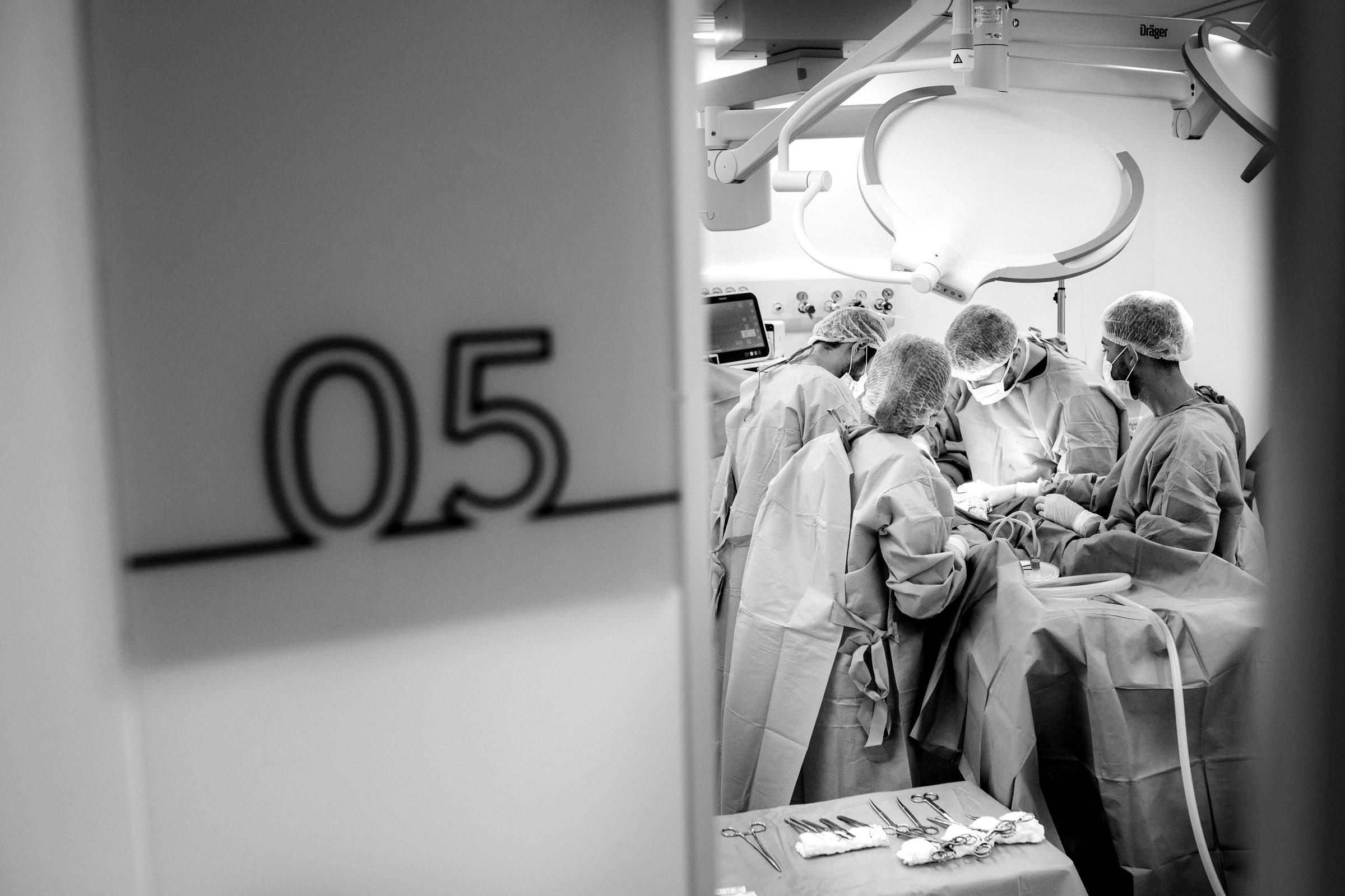 Surgeons at work, seen past the door of operating room 05