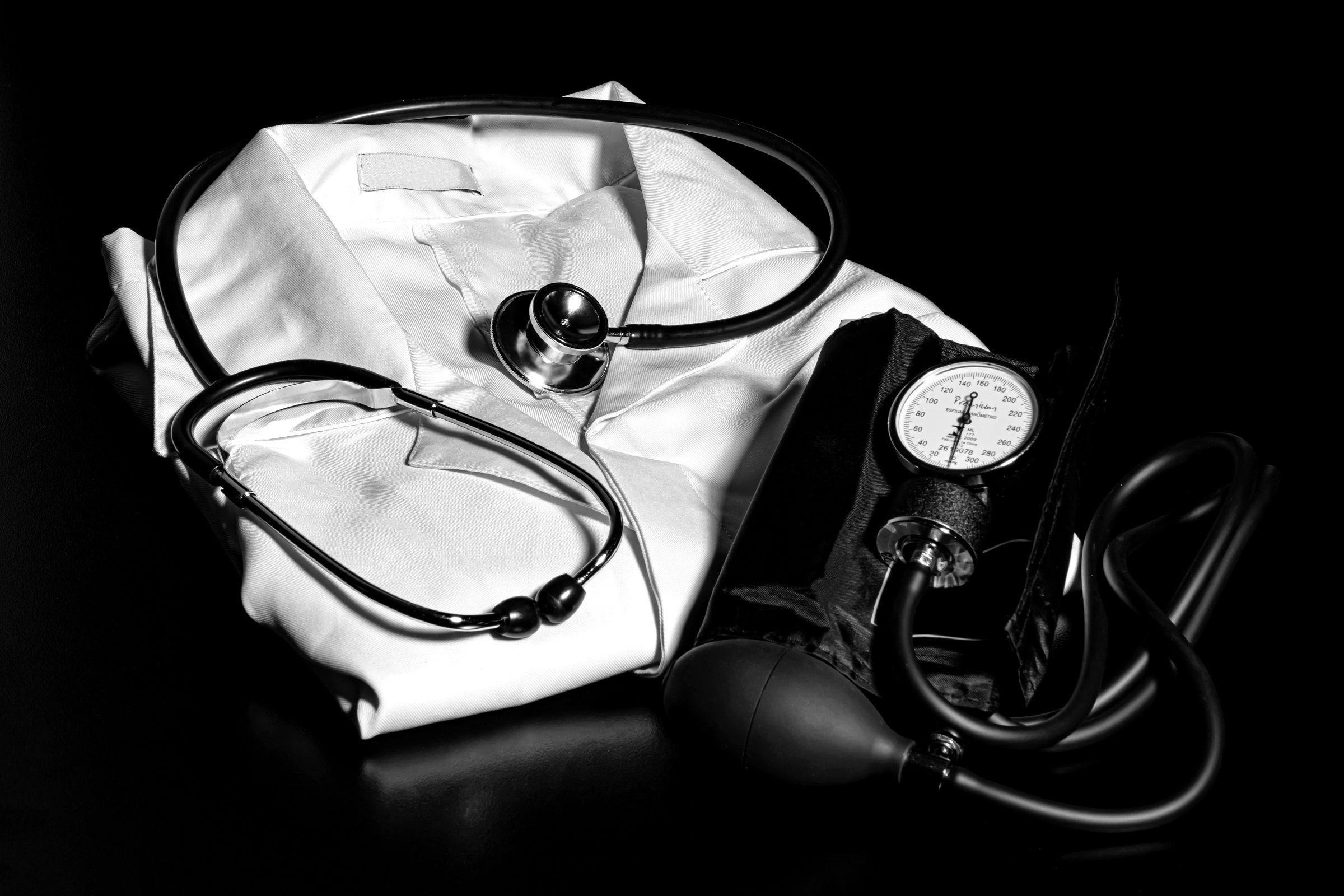 A stethoscope and blood pressure cuff resting on a folded white coat